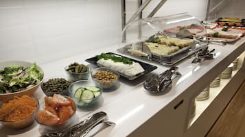 Un bufé con diversas opciones de comida, incluyendo ensaladas, frutas y carnes.