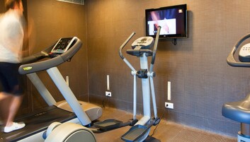 Una palestra con tapis roulant, ellittica e televisore a parete.