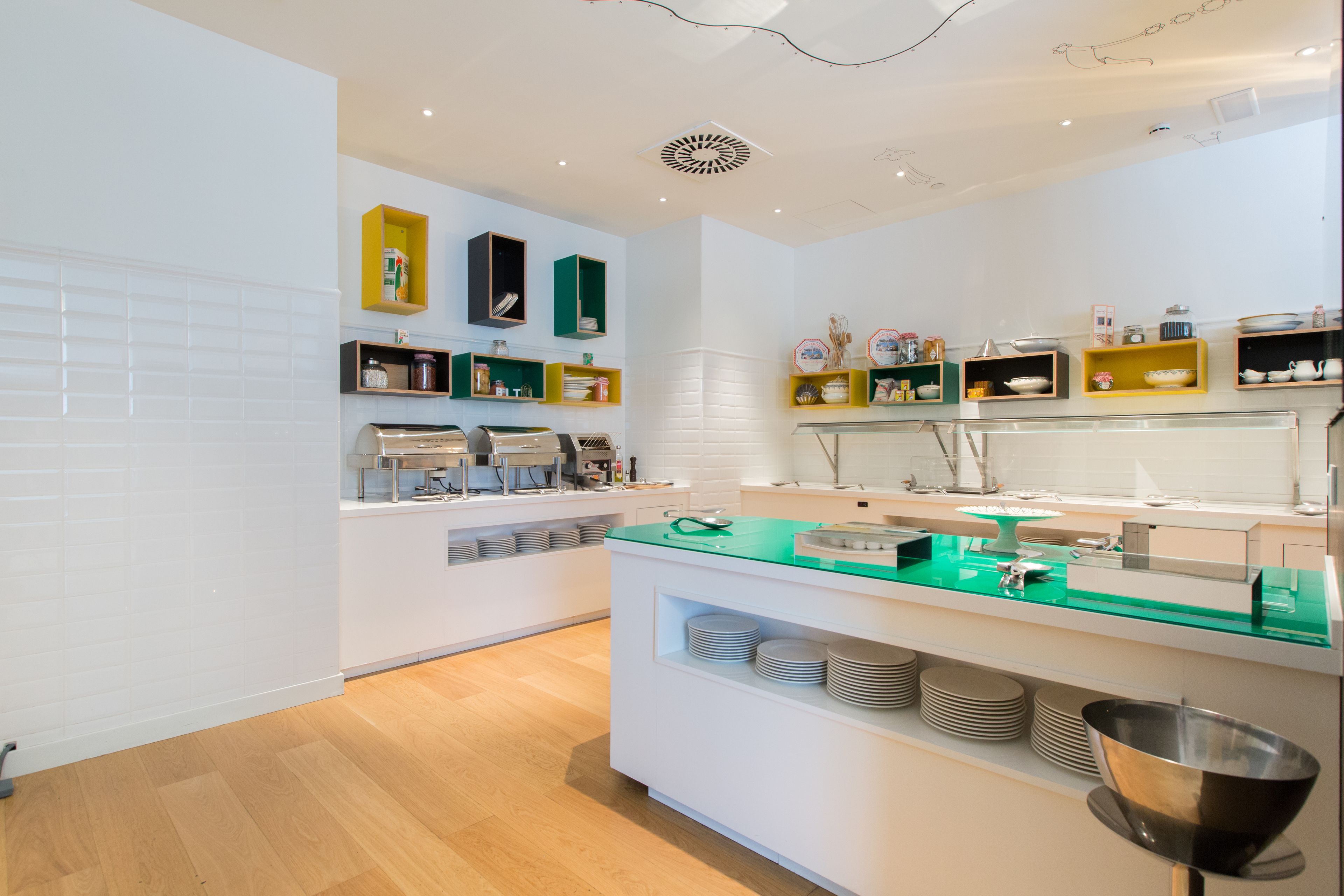 Una cocina moderna con armarios blancos, encimeras verdes y diversos electrodomésticos.