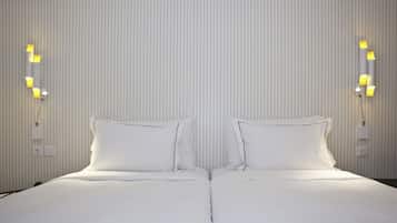 A double bed with white linens, two bedside tables with lamps, and a wall with vertical lines.