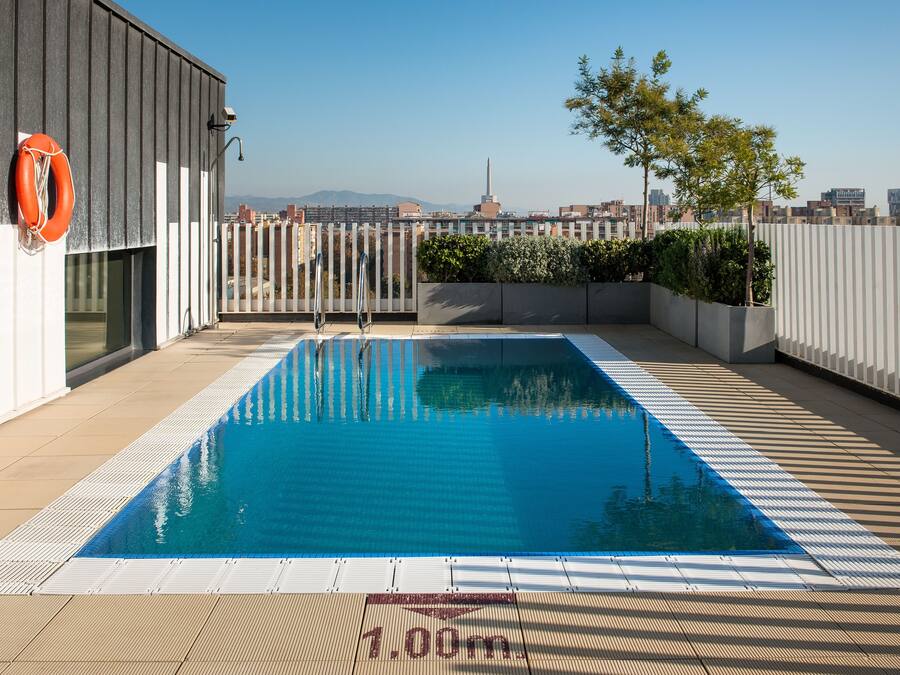 Una piscina al terrat amb vista despejada al perfil urbà, un flotador i una profunditat indicada de 1,00m.
