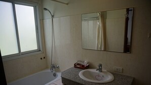 Un baño con bañera, lavamanos, espejo y ventana.