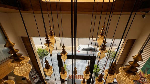 A modern interior with hanging pendant lights, a view through a large window, and a seating area with a sofa. - Quality Inn Gurgaon (Gurugram)