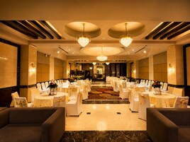 A banquet hall with round tables and chairs, chandeliers, and a carpeted floor.