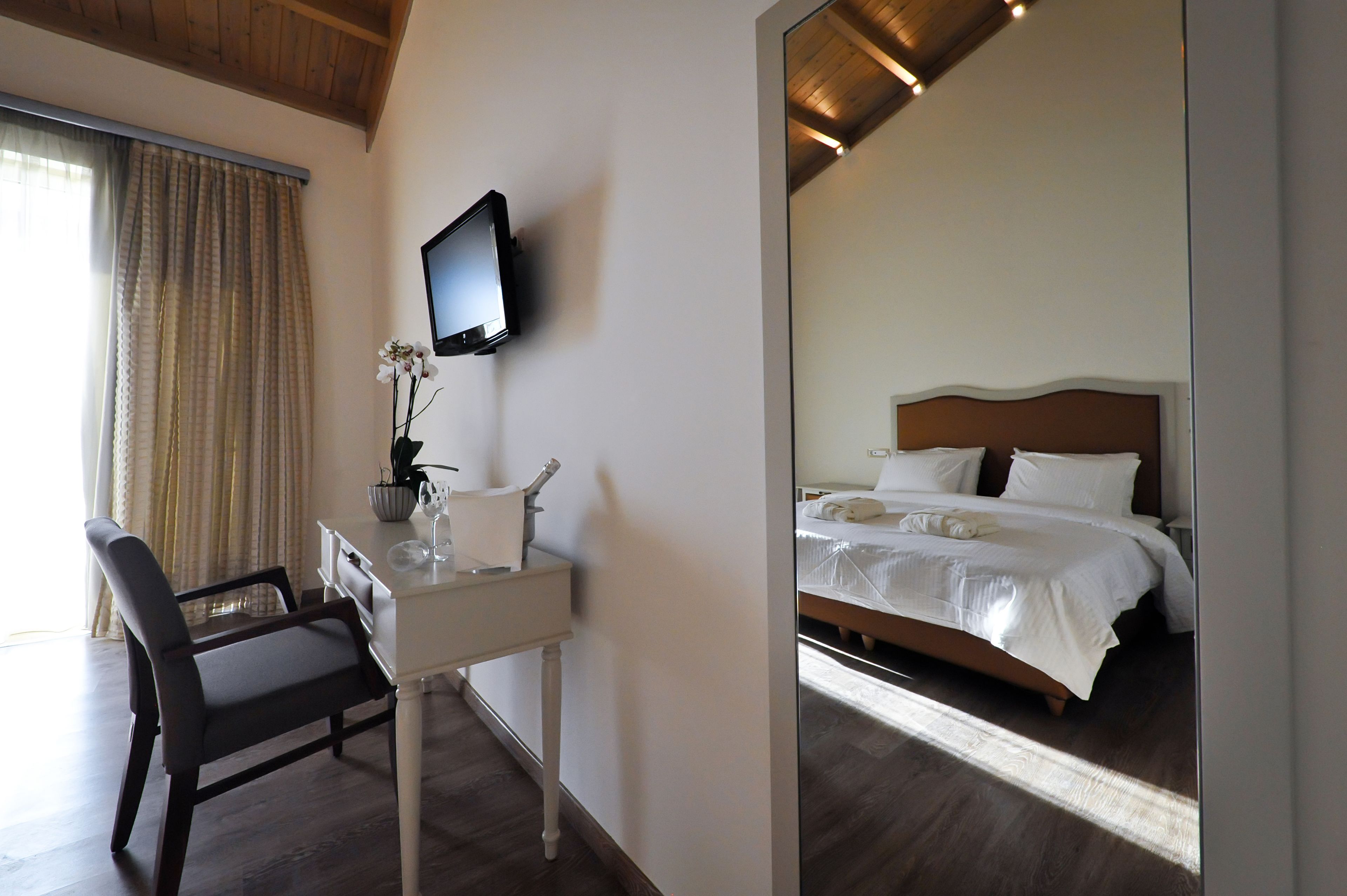 A hotel room with a bed, a desk, a chair, a television, and a window with curtains.