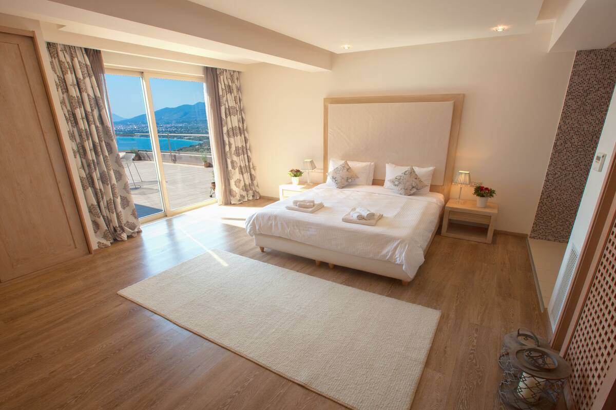 Une chambre spacieuse avec un grand lit, une vue sur la mer et un balcon.