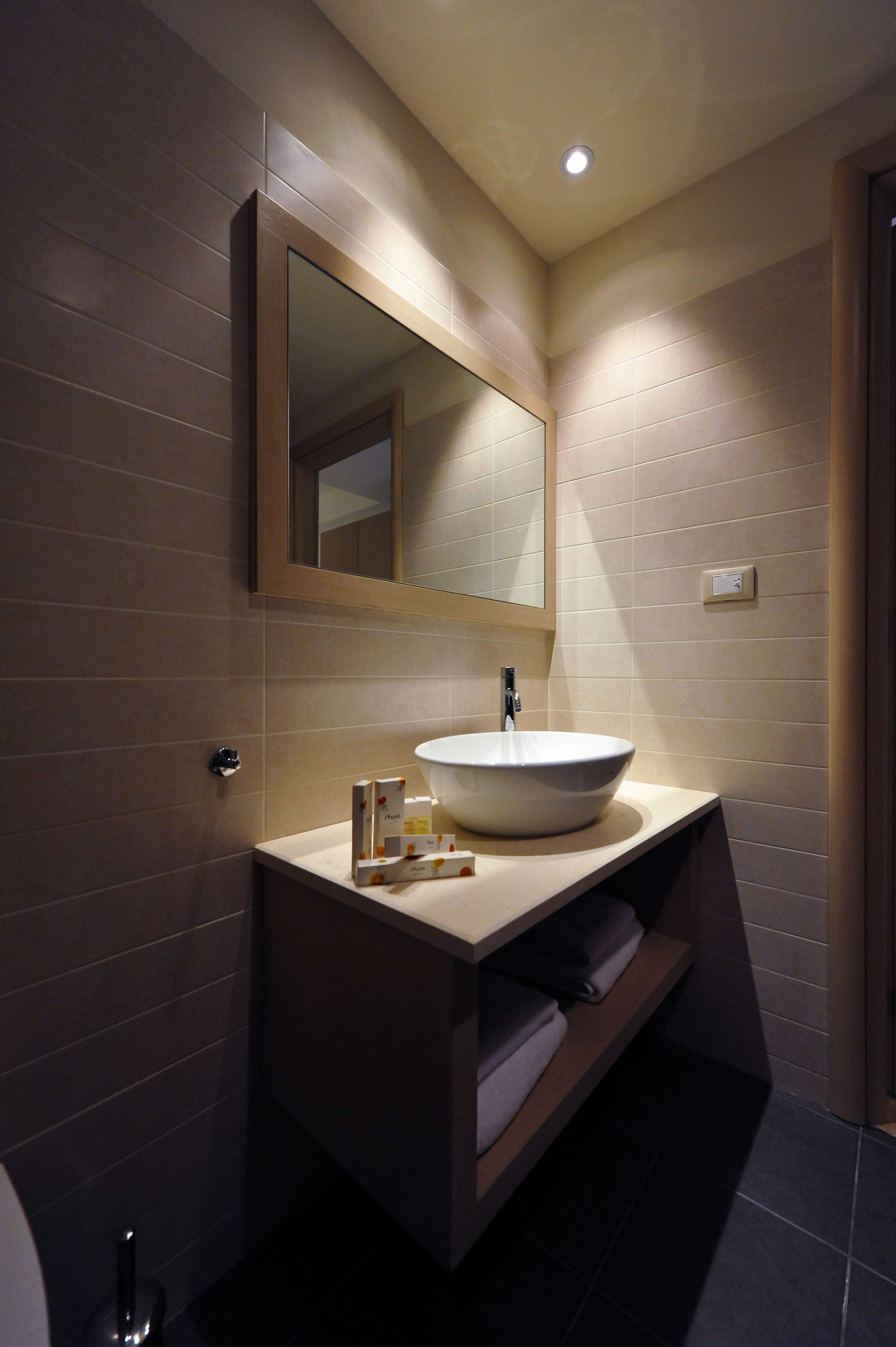 A modern bathroom with a large mirror, a vessel sink, and a towel rack.