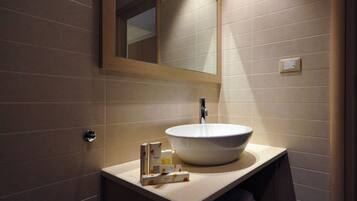 A modern bathroom with a large mirror, a vessel sink, and a towel rack.
