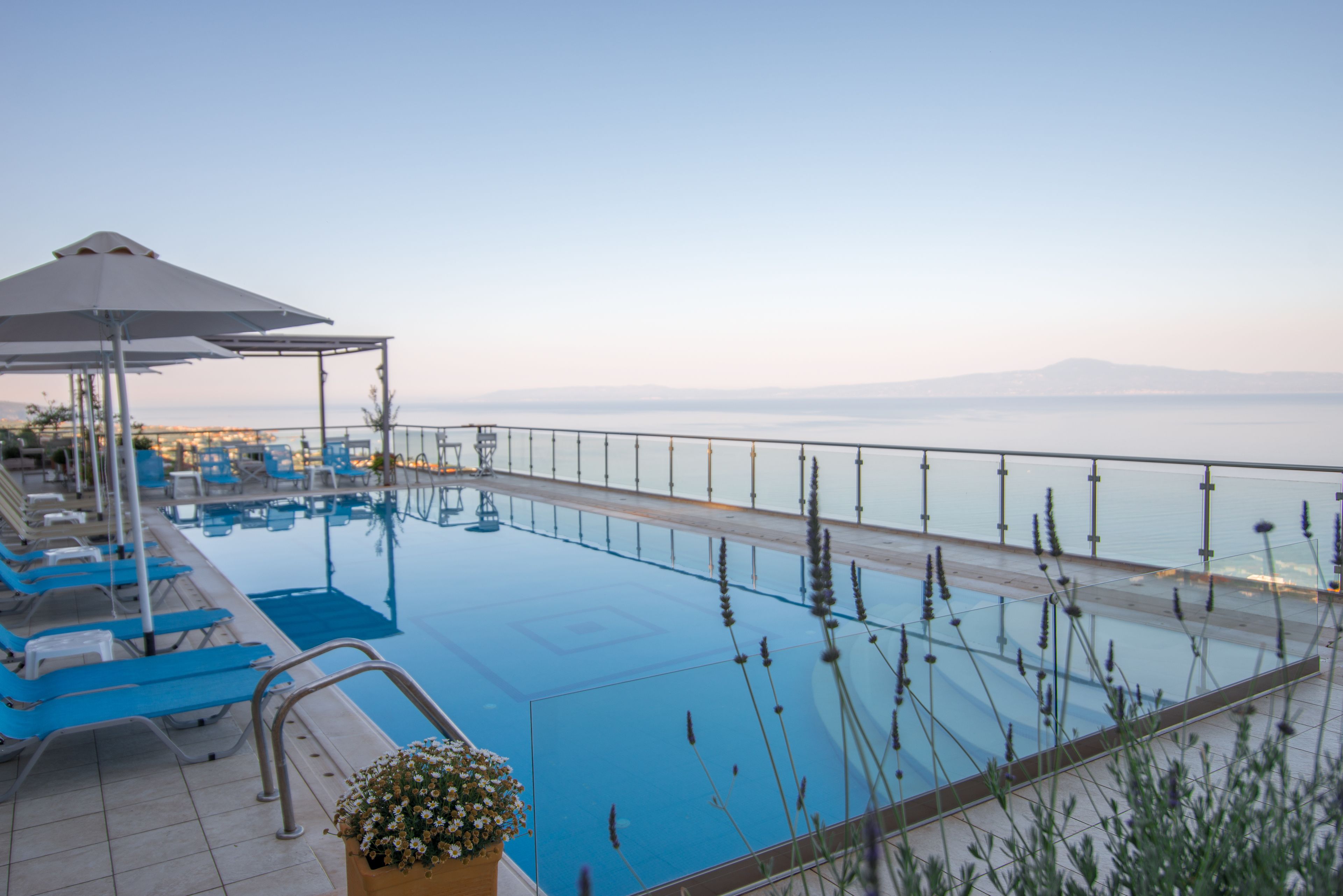 A poolside area with lounge chairs and a covered seating area, overlooking a body of water.