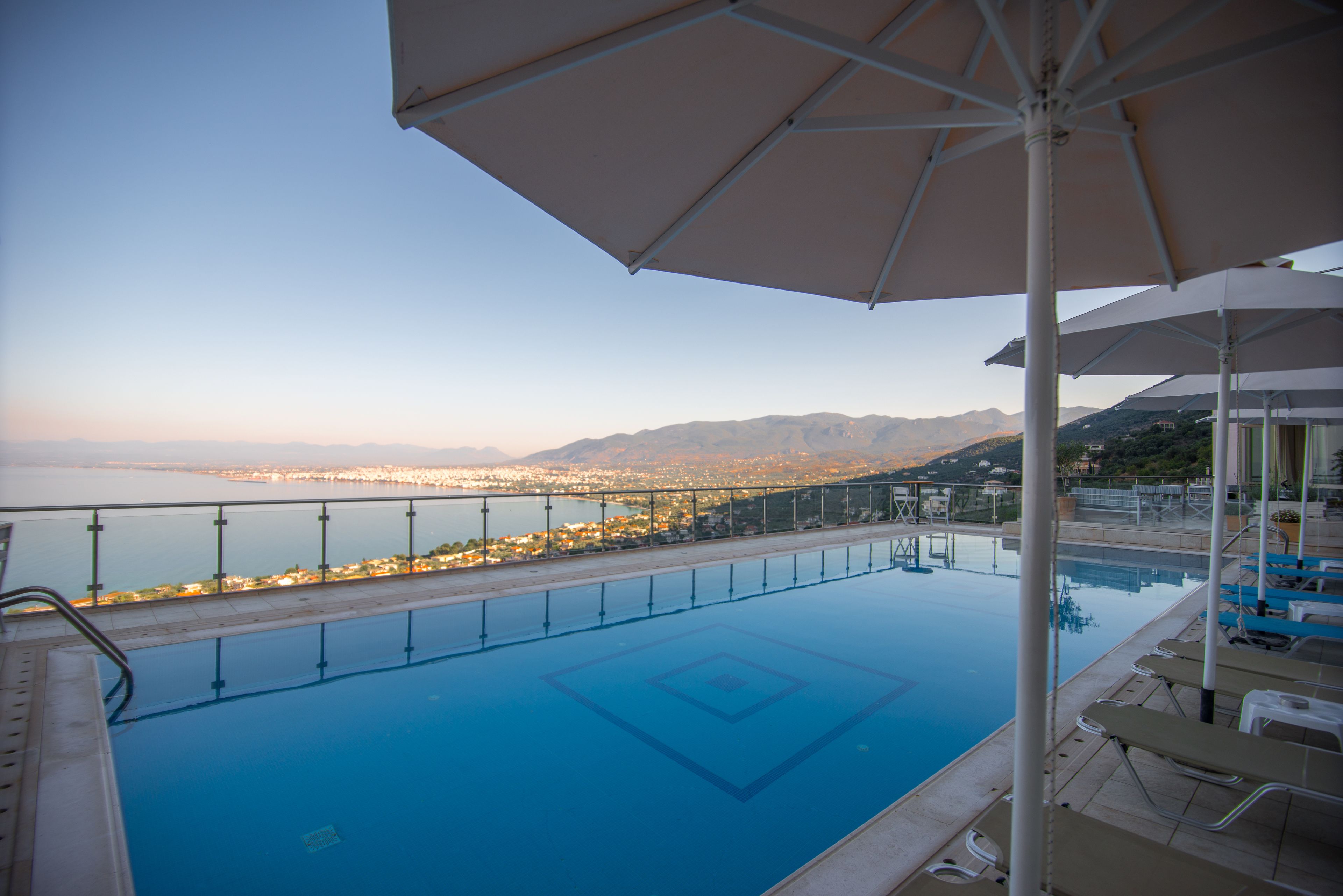 On voit clairement une piscine, avec une vue sur la ville et des montagnes en arrière-plan.