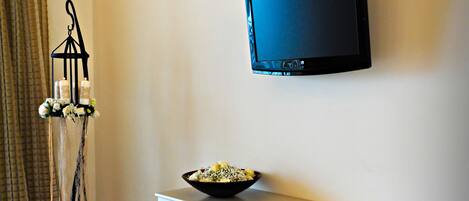 A room with a desk, chair, and a mounted television.