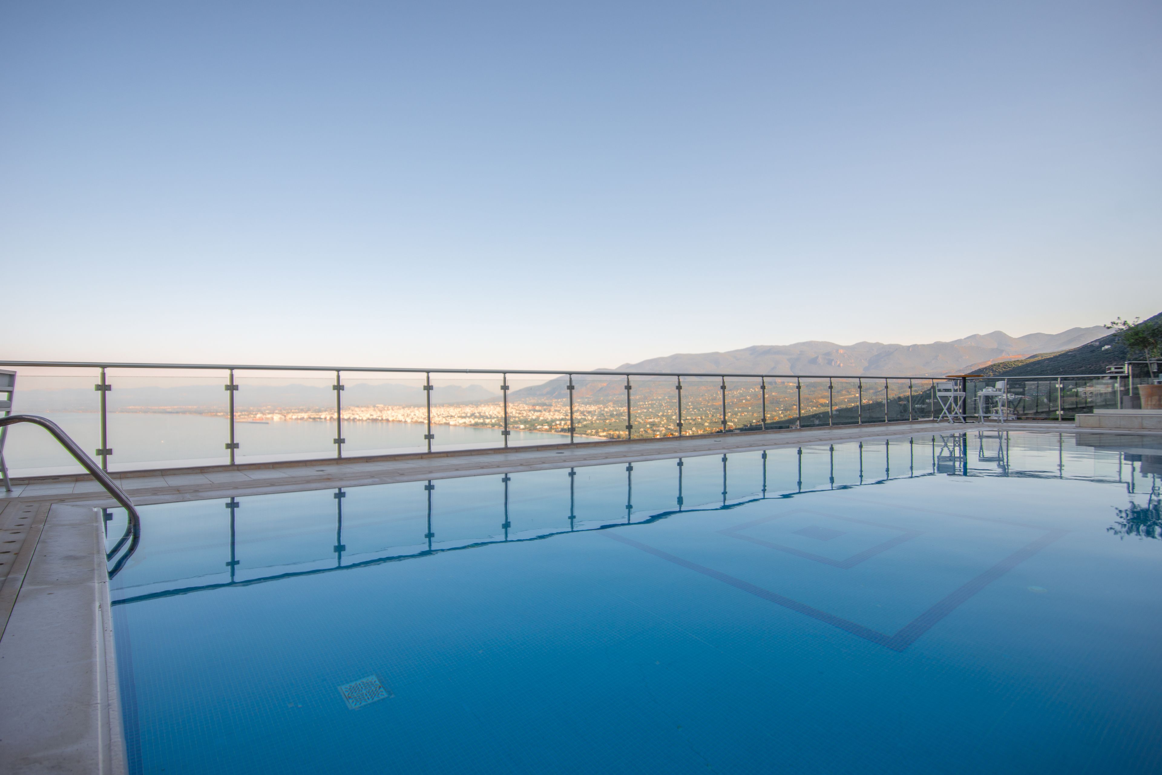 Vista despejada de una piscina con barandilla metálica y un paisaje urbano al fondo.