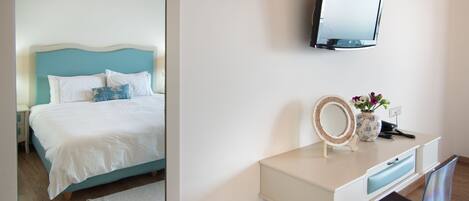 Un dormitorio con una cama, una mesita de noche, un aparador, un espejo y un televisor en la pared.