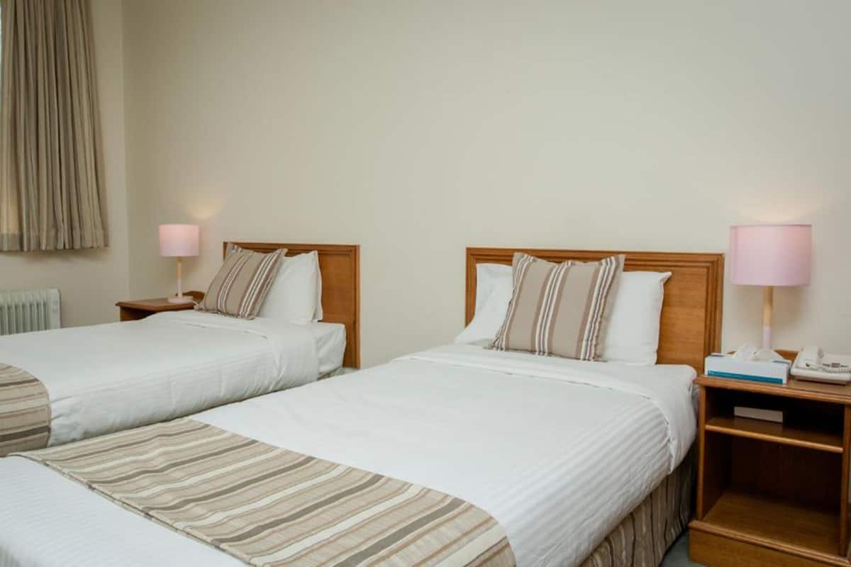 Two single beds with wooden headboards, white bedding, and bedside lamps.