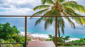 A balcony with a view of the ocean and a palm tree. - Scenic Matavai Resort Niue (Tamakautoga)