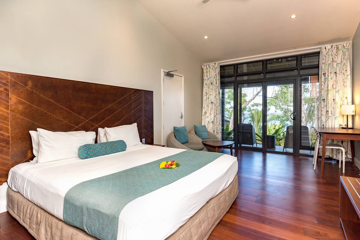 A well-appointed hotel room with a large bed, a sitting area with a view, and a dining table.