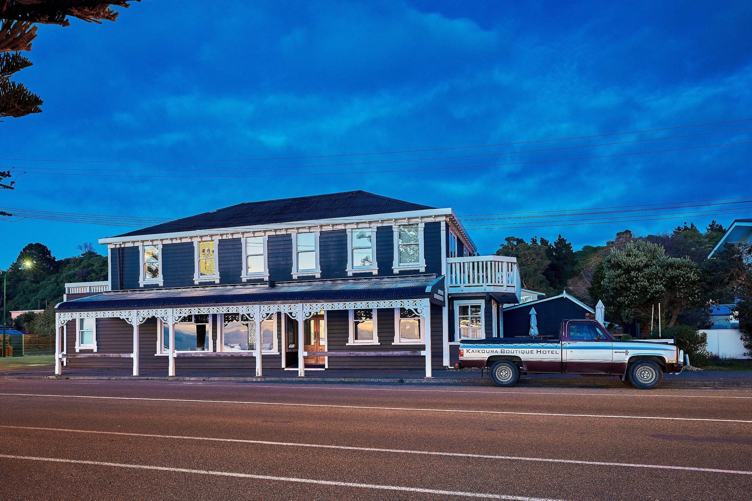 A two-story building with a balcony and a vintage car parked in front.