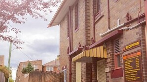 Zona de recepción con un edificio de ladrillo, un mostrador de recepción y un cartel que muestra tarifas económicas.