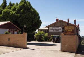 A mountain lodge with a signboard, a brick wall, and a parked vehicle. - Katoomba Mountain Lodge (Katoomba)