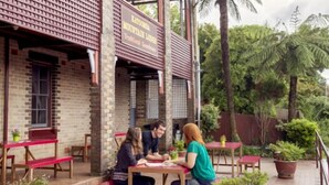 Un restaurante con terraza, paredes de ladrillo y macetas con plantas.