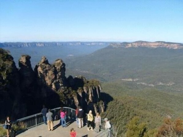 A scenic overlook with a metal railing, offering views of a mountainous landscape.