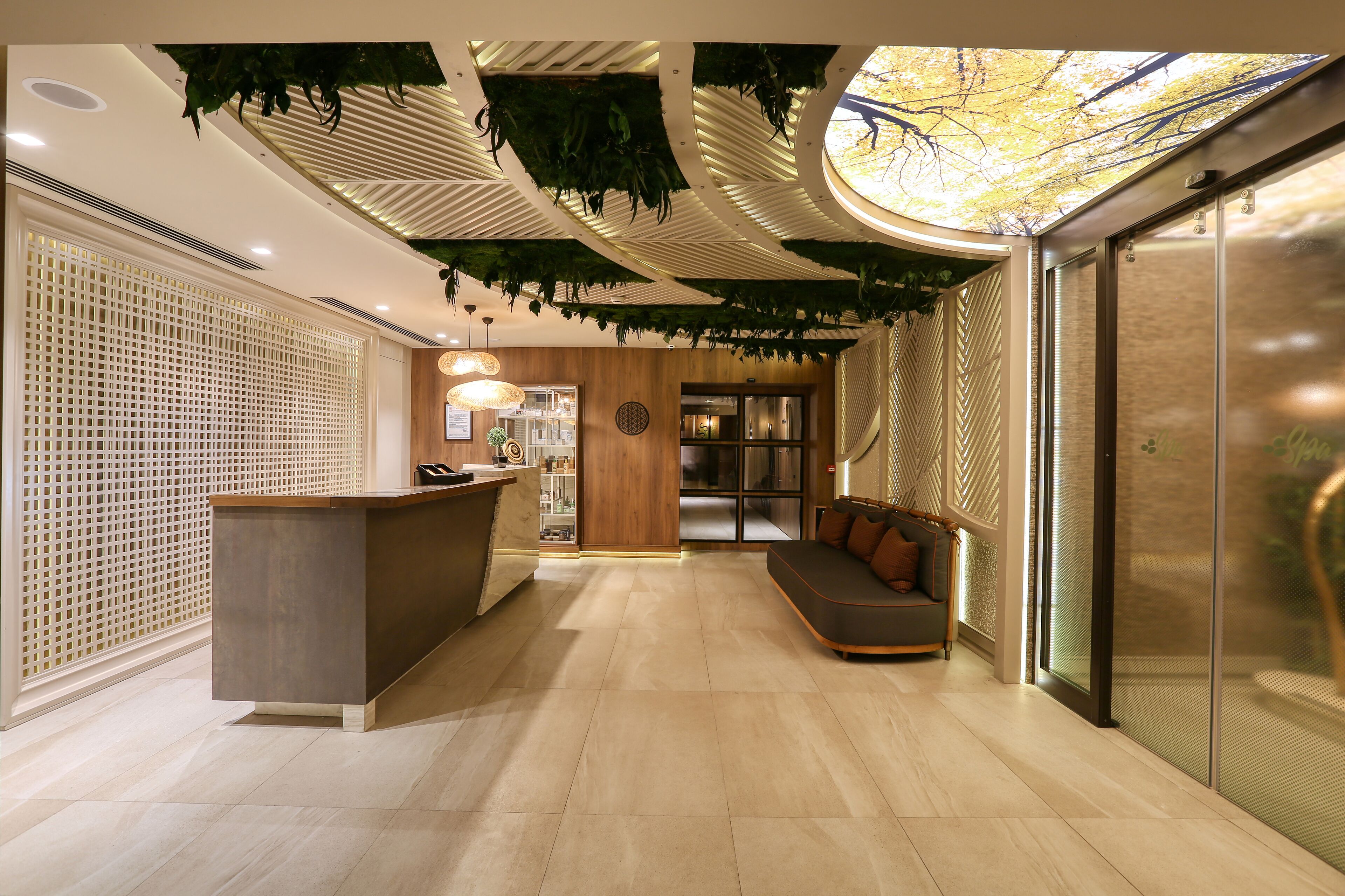 A modern reception area with a wooden reception desk, a seating area with a sofa, and a glass partition.