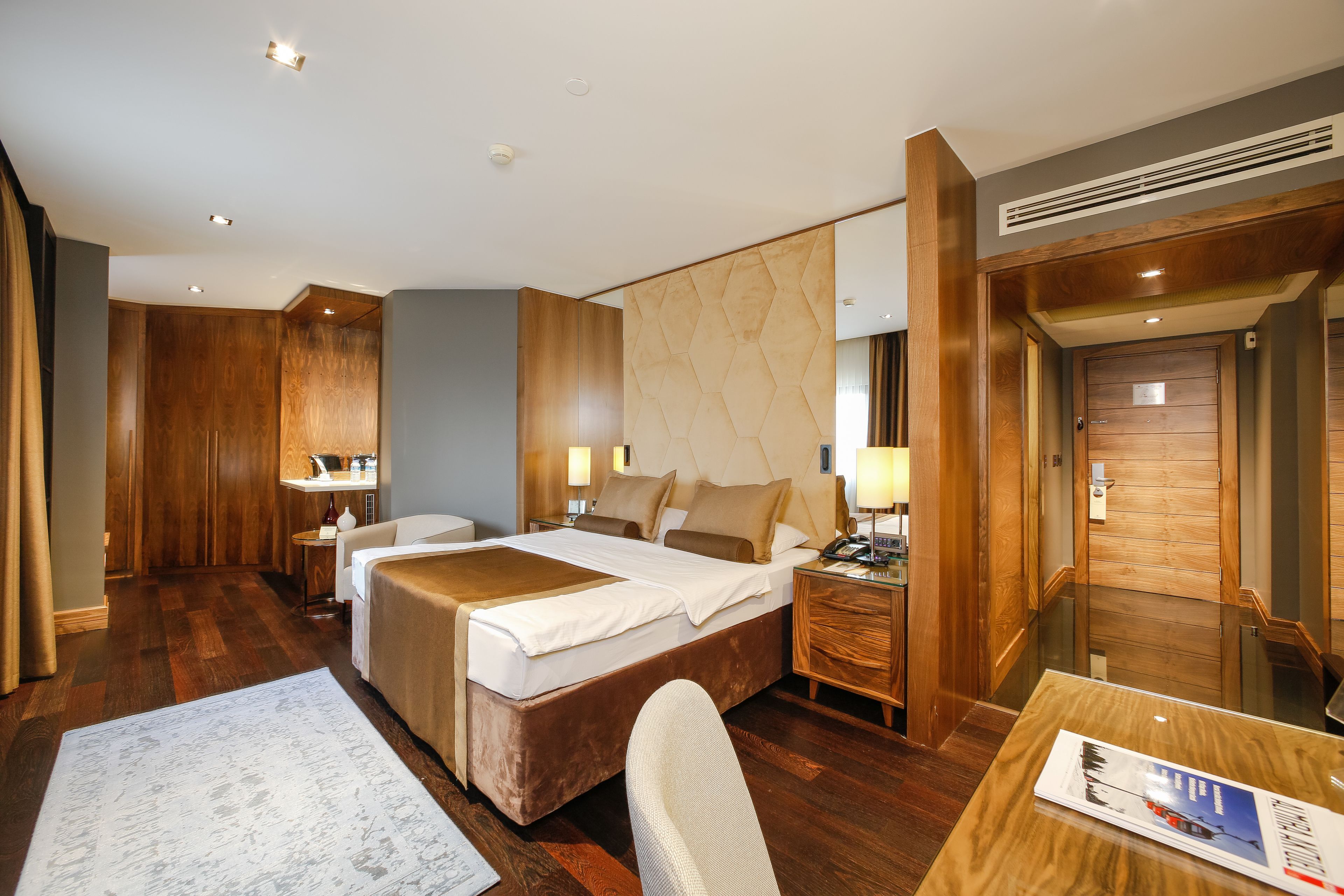 Una habitación de hotel con una cama grande, mesitas de noche, un escritorio y una silla.