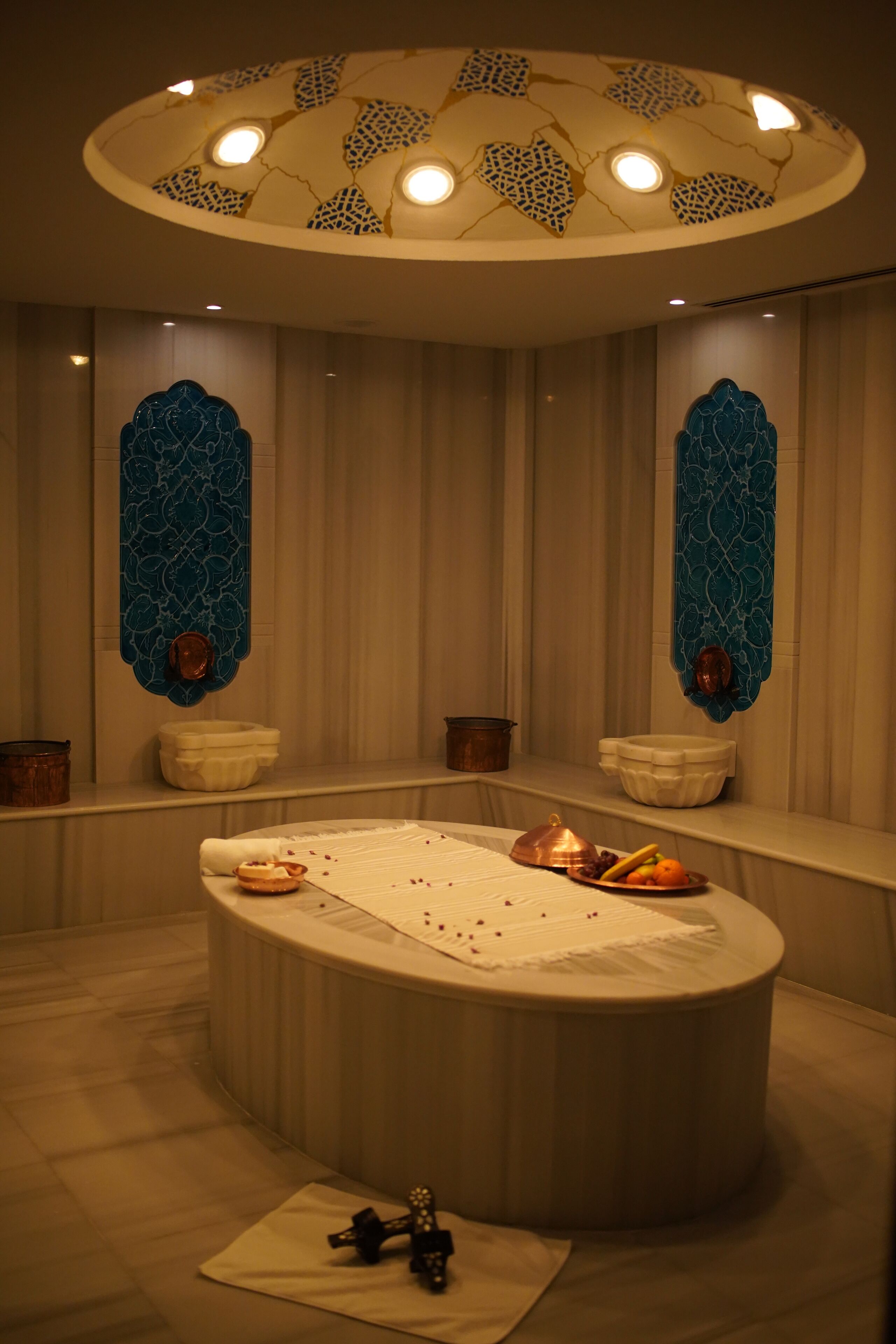 A spa room with a large oval bathtub, decorative wall sconces, and a ceiling light fixture.
