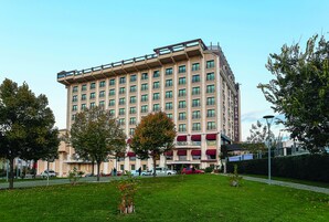 Un hotel de varios pisos con fachada plana, balcones y un césped bien cuidado.