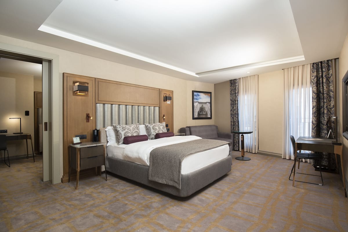 Een hotelkamer met een groot bed, een bureau, een stoel en een tafeltje.