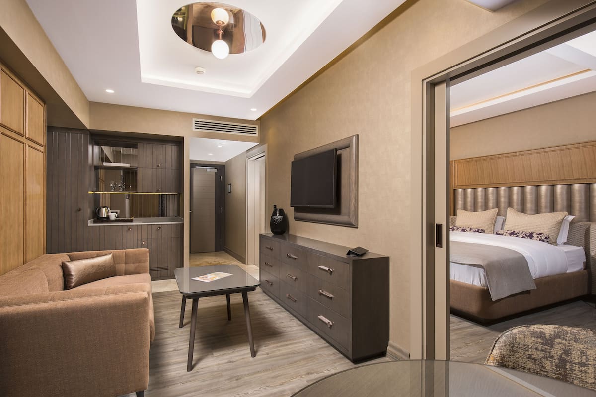 Een moderne hotelkamer met een bank, een tafeltje, een televisie, een bed en een minibar.