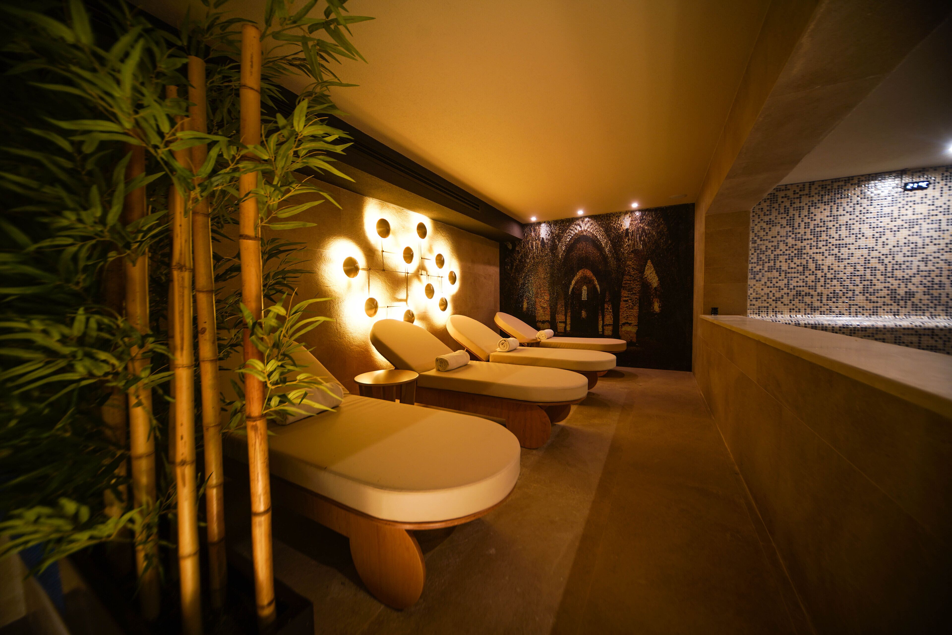 A spa room with massage chairs, a wall with circular light fixtures, and a mosaic wall.