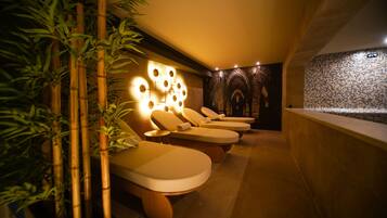 A spa room with massage chairs, a wall with circular light fixtures, and a mosaic wall.