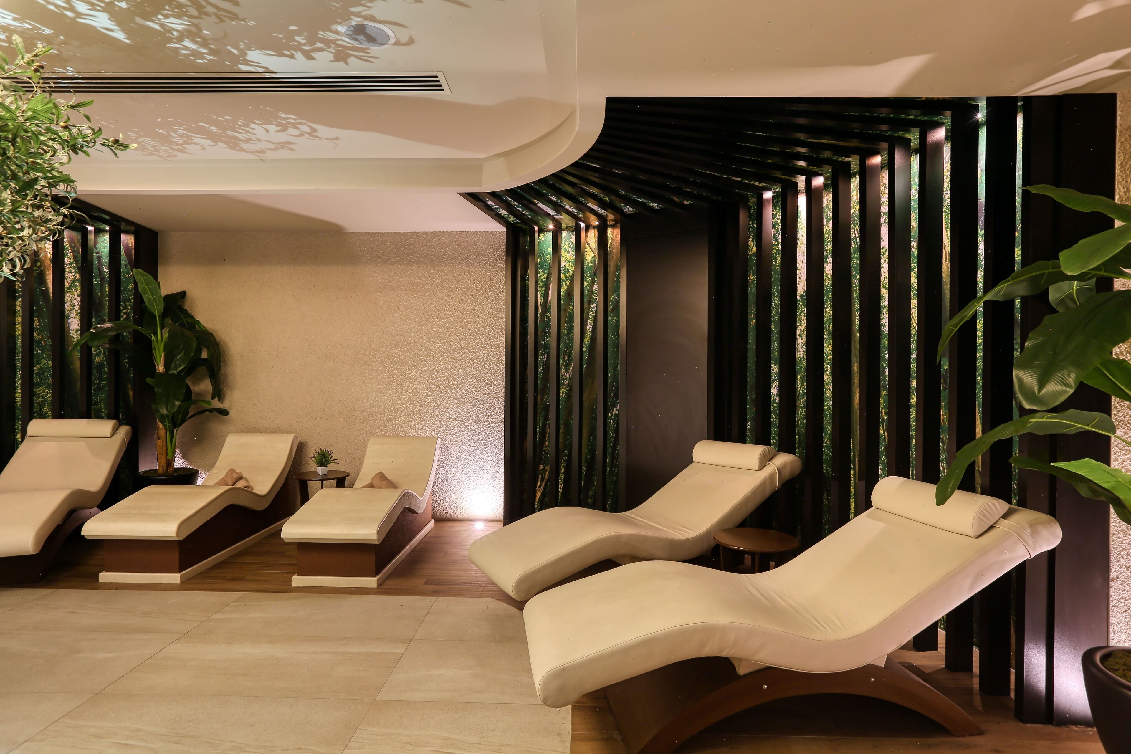 A spa area with reclining chairs, a ceiling projector, and vertical greenery panels.