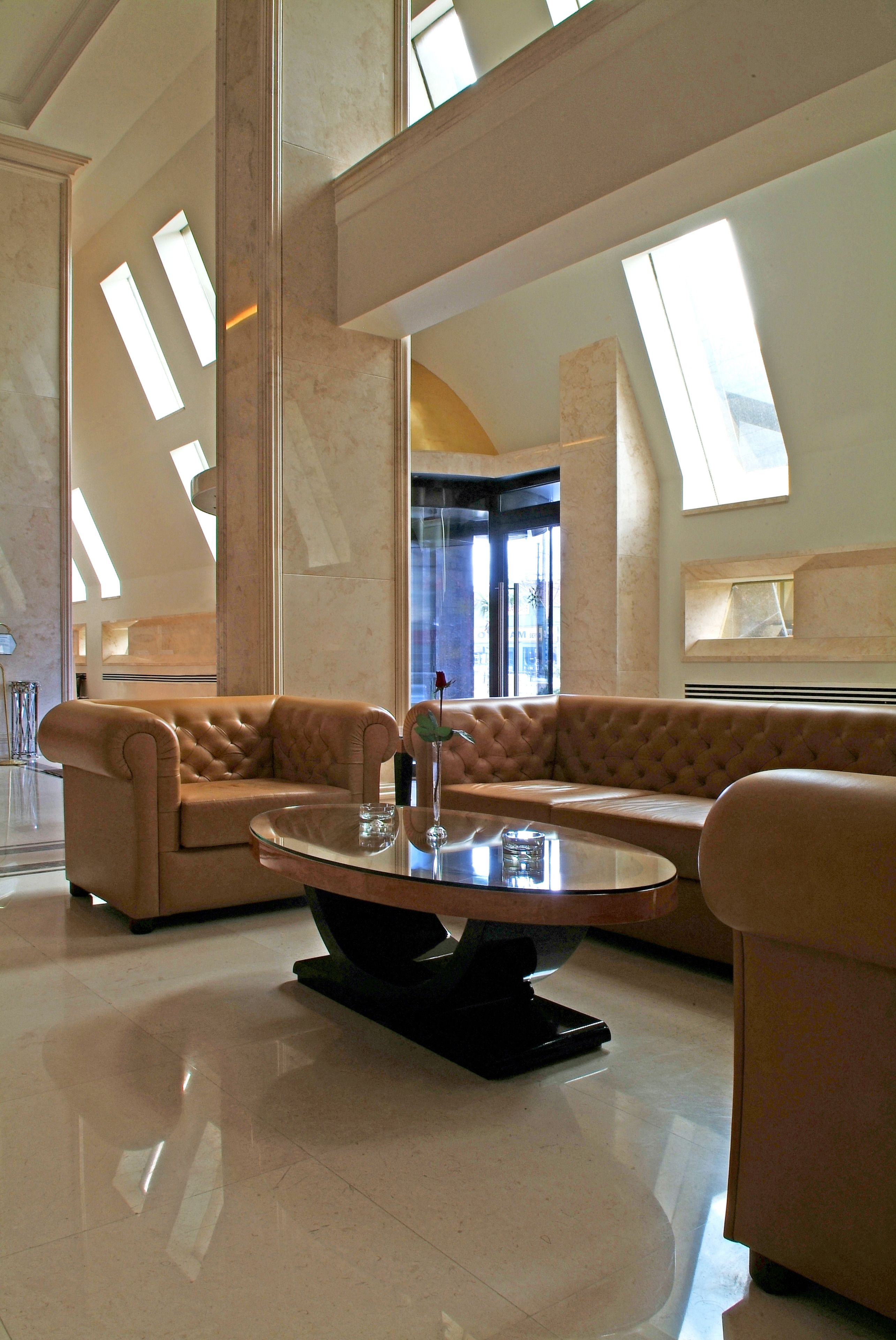 A spacious lobby with high ceilings, a large central coffee table, and a seating area with sofas.
