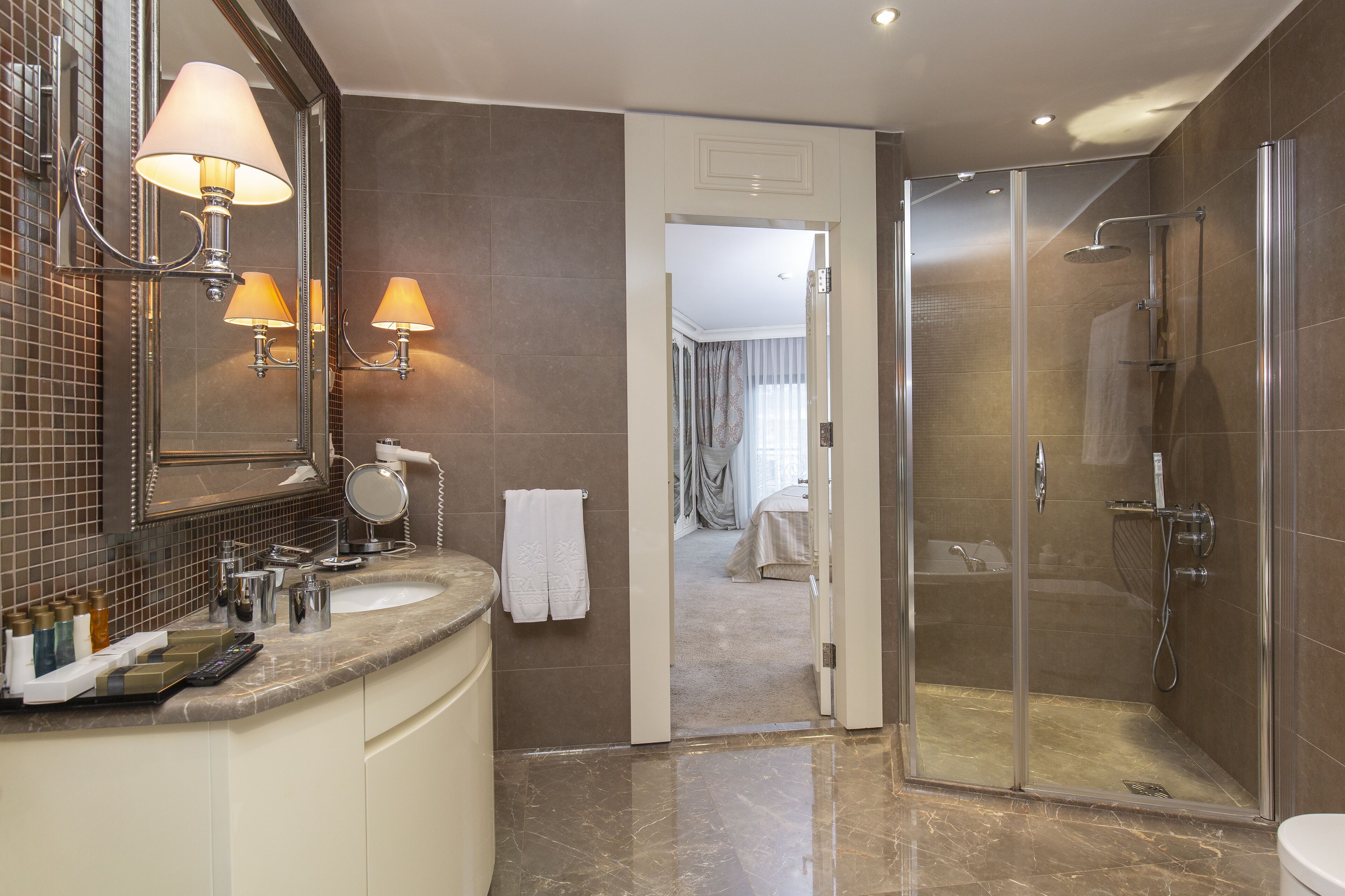 A modern bathroom with a marble vanity, a large mirror, and a glass-enclosed shower.