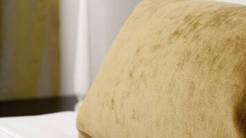 A bed with a beige pillow and a white lamp in the background.