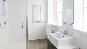 Un bagno moderno con box doccia in vetro, lavandino bianco e uno specchio grande.