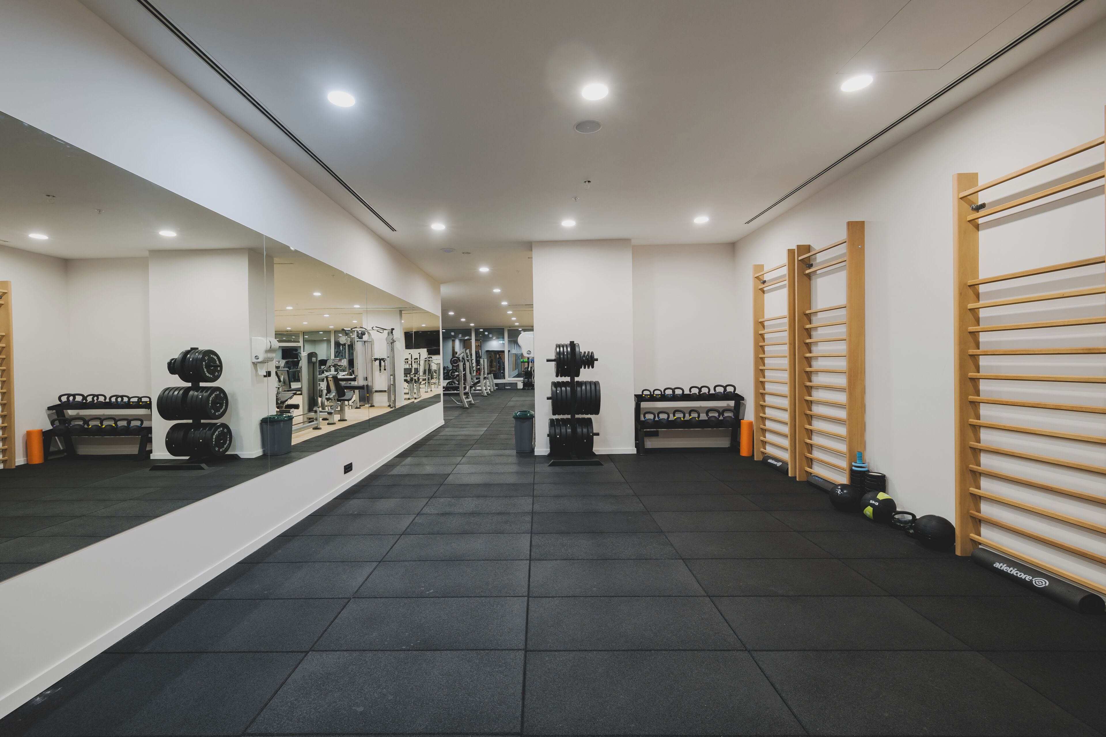 Uma academia com piso de borracha preta, racks de peso e equipamentos de exercício.