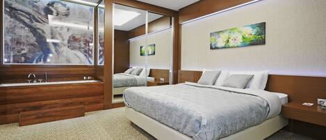 Un dormitorio moderno con una cama grande, una bañera integrada y un espejo amplio.