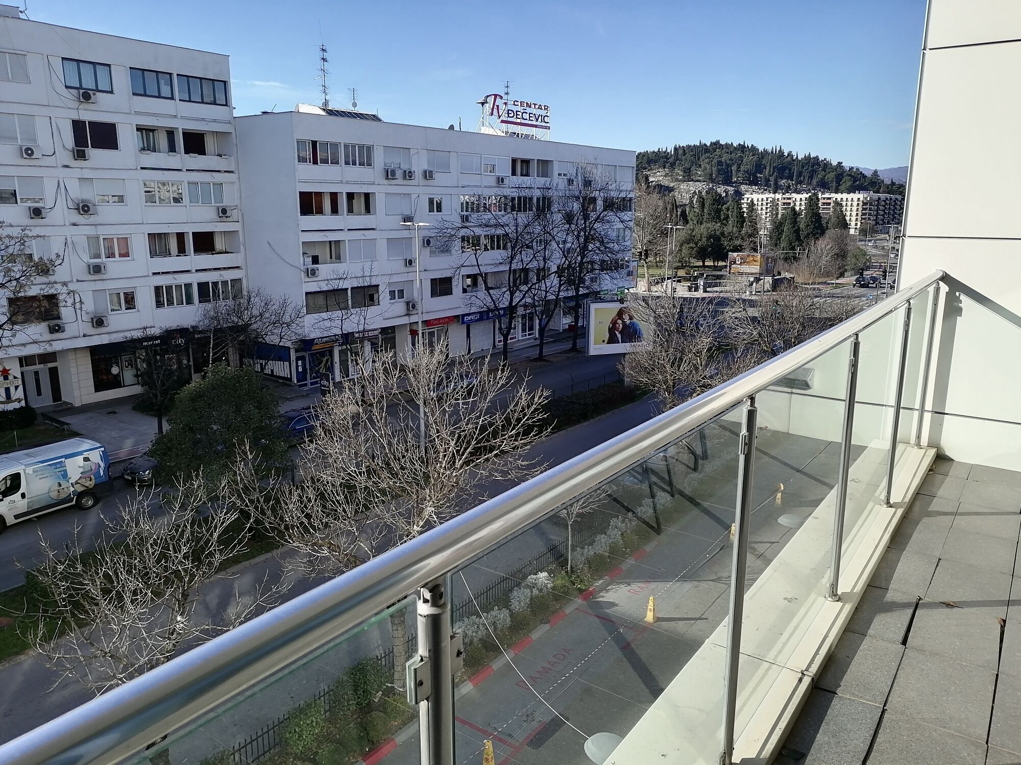 A multi-story building with a central atrium, surrounded by trees and a clear sky.