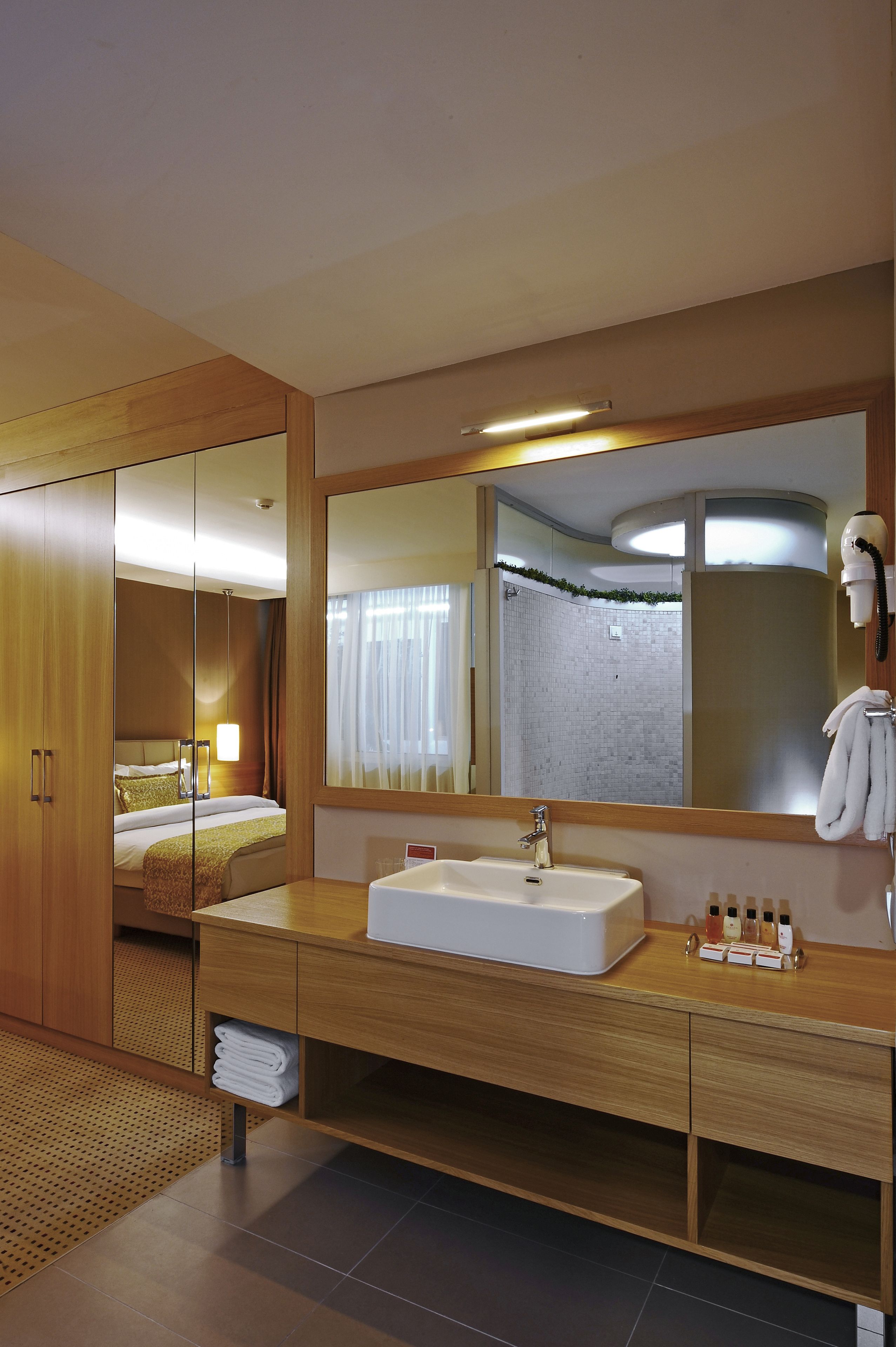 Un baño de hotel con un espejo grande, un lavabo, tocador y zona de ducha.