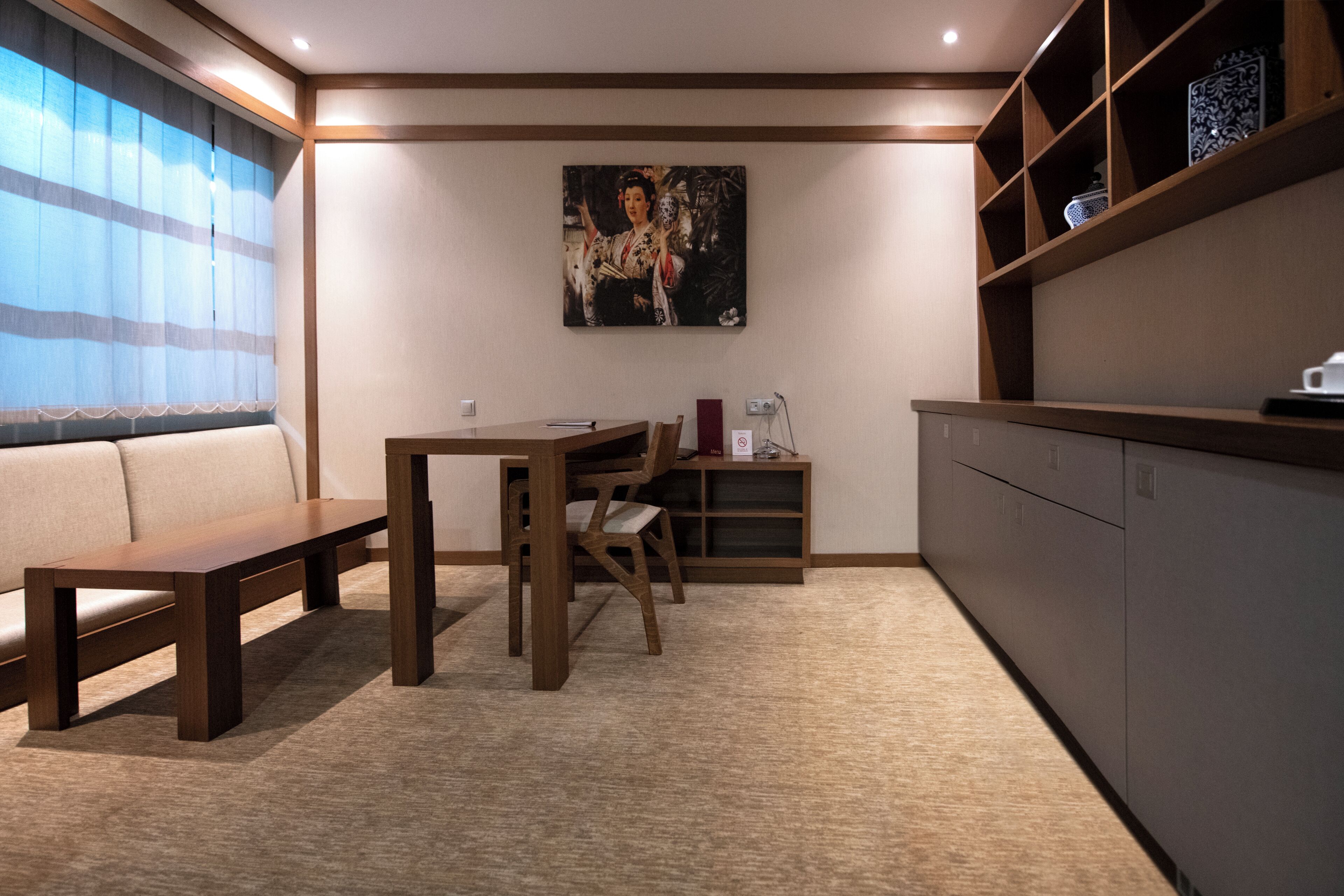 Ein modernes Zimmer mit einer hölzernen Bank, einem Esstisch und Stühlen. An der Wand hängt ein Gemälde und ein Regal mit Dekorationen.
