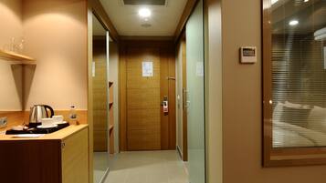 A hotel hallway with a wooden counter, a kettle, and a water bottle.