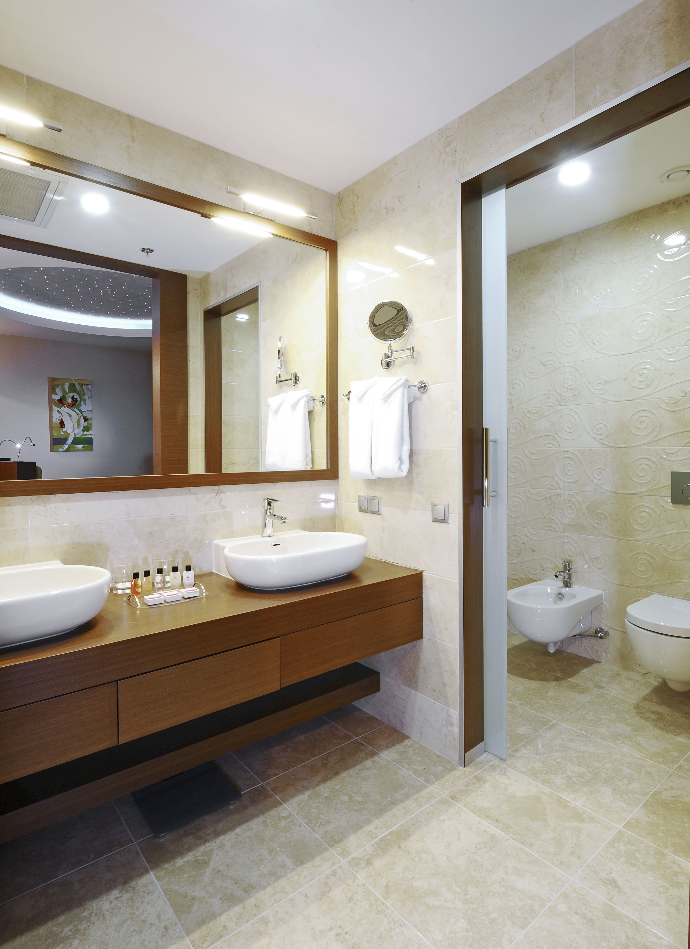 Un baño moderno con dos lavamanos, un espejo grande y un bidé.