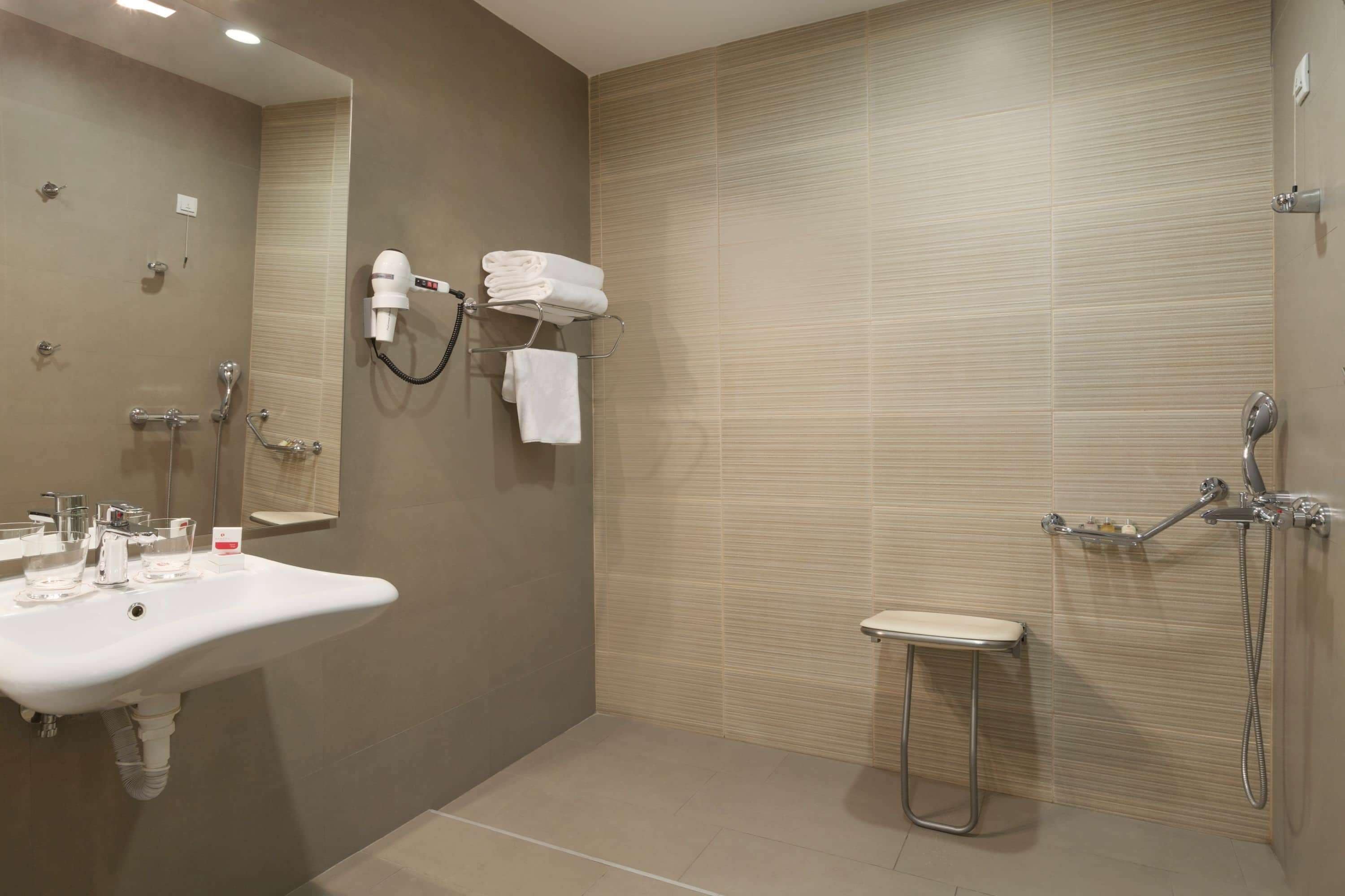 A modern bathroom with a sink, mirror, towel rack, and shower.