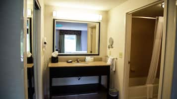 A bathroom with a sink, mirror, and shower.