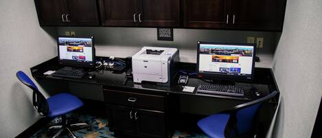 A workspace with two desks, each with a computer, a printer, and a chair.