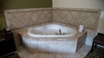 A corner bathroom with a freestanding bathtub, a vanity with a telephone, and a patterned rug.