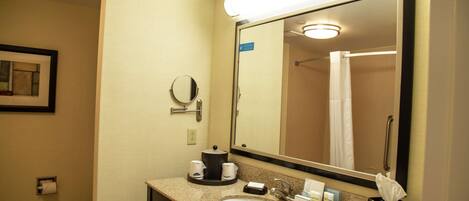 A hotel bathroom with a sink, mirror, and toilet.